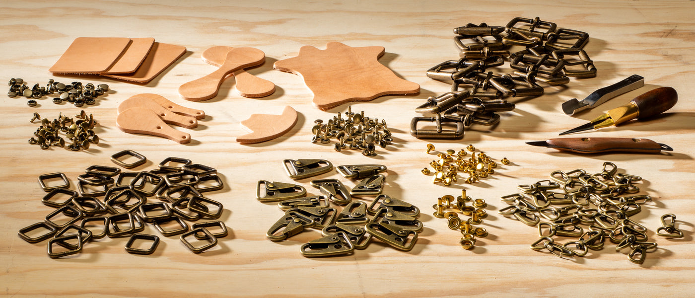 Assorted leathercraft hardware and leather pieces laid out on a wooden table.