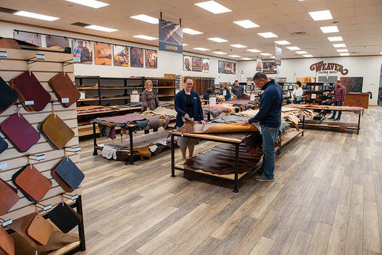 Customers browsing leather hides and supplies inside the Weaver Leather Supply retail store.
