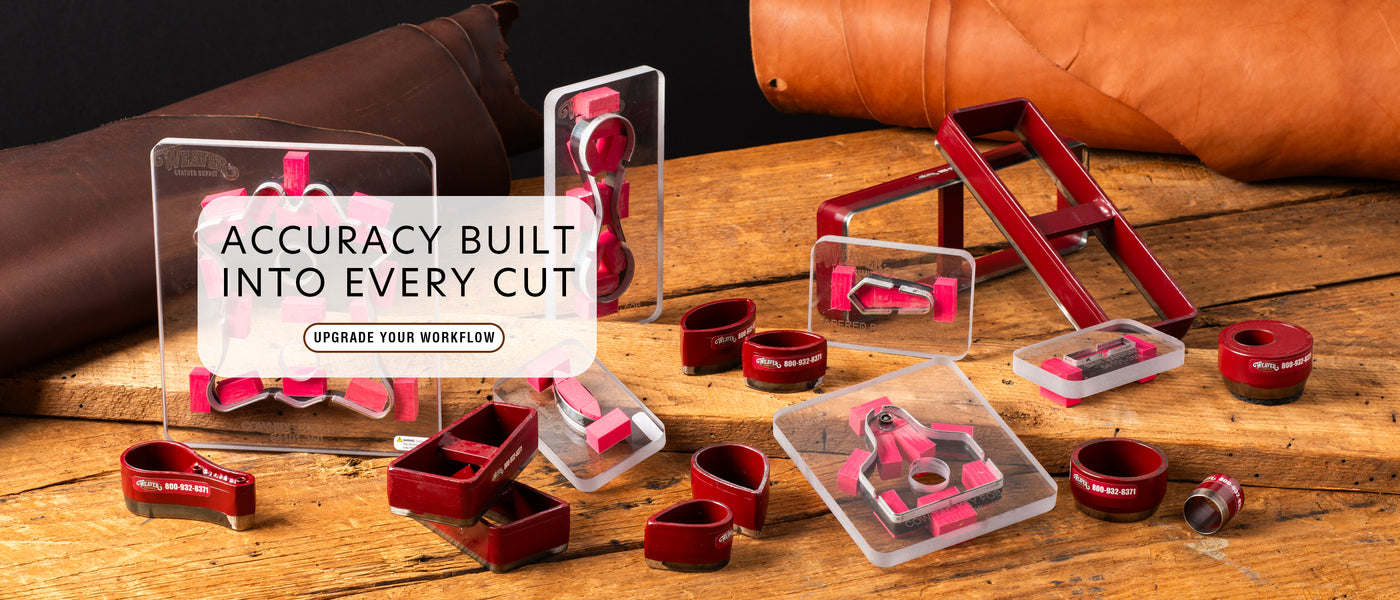 Red leather clicker dies and cutting templates displayed on a wooden workbench with leather hides in the background.