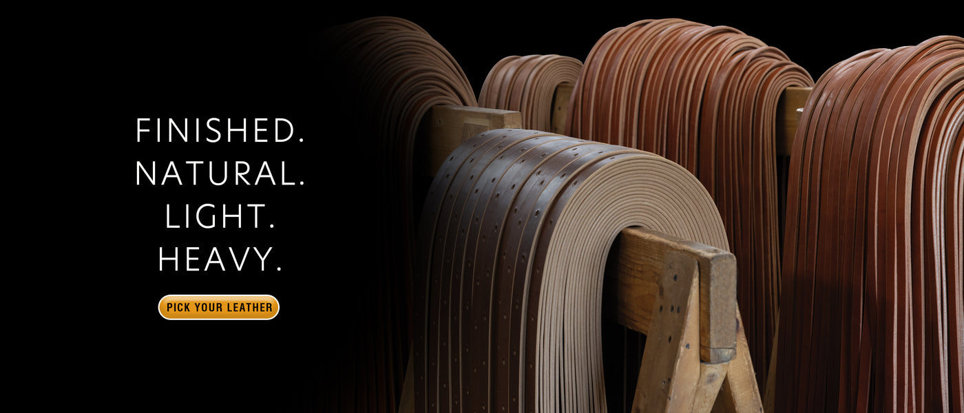 Finished leather straps in natural, light, and heavy weights hanging over wooden racks.