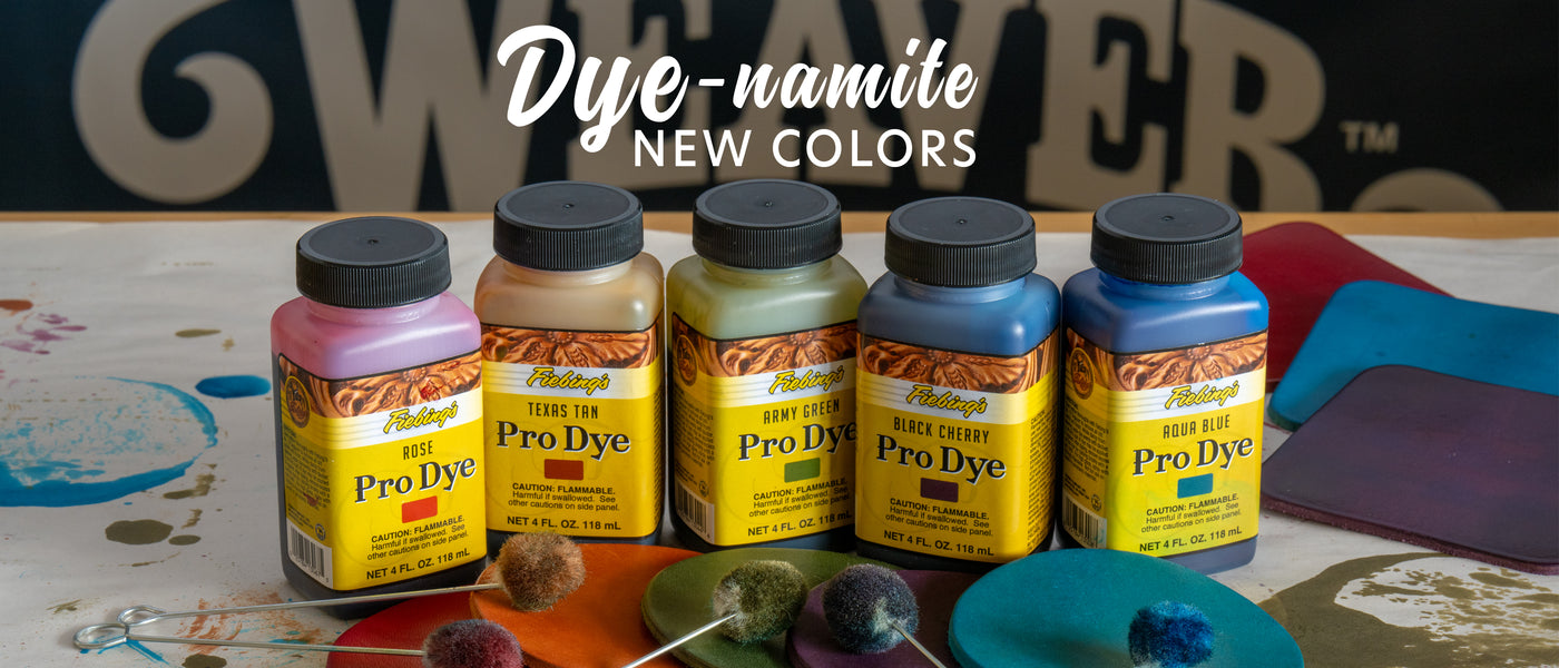 Five bottles of Pro Dye with colorful labels on a table with art supplies.